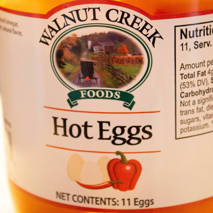 Close-up of Walnut Creek Foods label on a glass jar of hot pickled eggs featuring a red chili pepper illustration and farm landscape, part of USA Made, Kitchen & Food, Pantry, and Best Sellers collections.