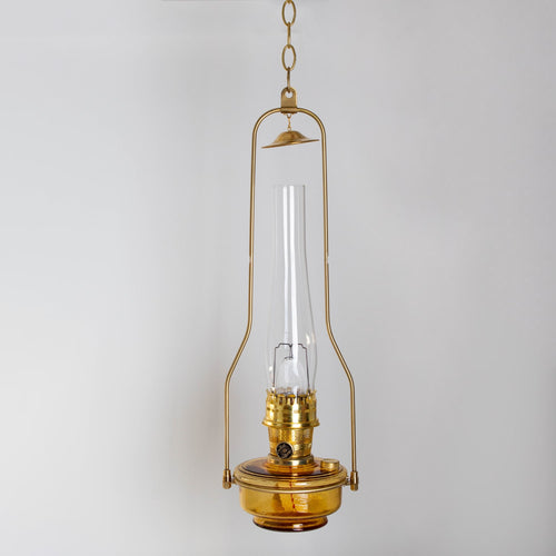 Handcrafted amber glass hanging oil lamp with gleaming brass tilt-frame hanger, ideal for lamps & lighting, farm, garden & tool, and emergency supplies collections.