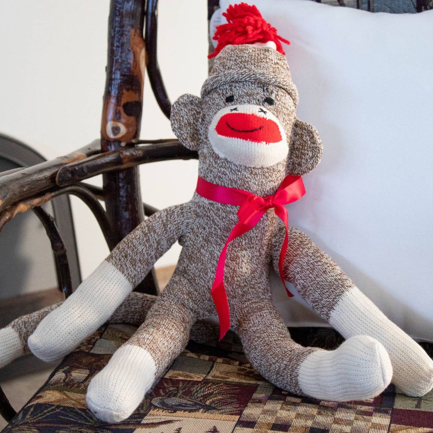 Handcrafted sock monkey made in USA from vintage red-heeled socks, featuring a bright red yarn pom-pom hat, red ribbon bow, and fiberfill stuffing, shown in Toys, Books & Games and Children's Toys collections.