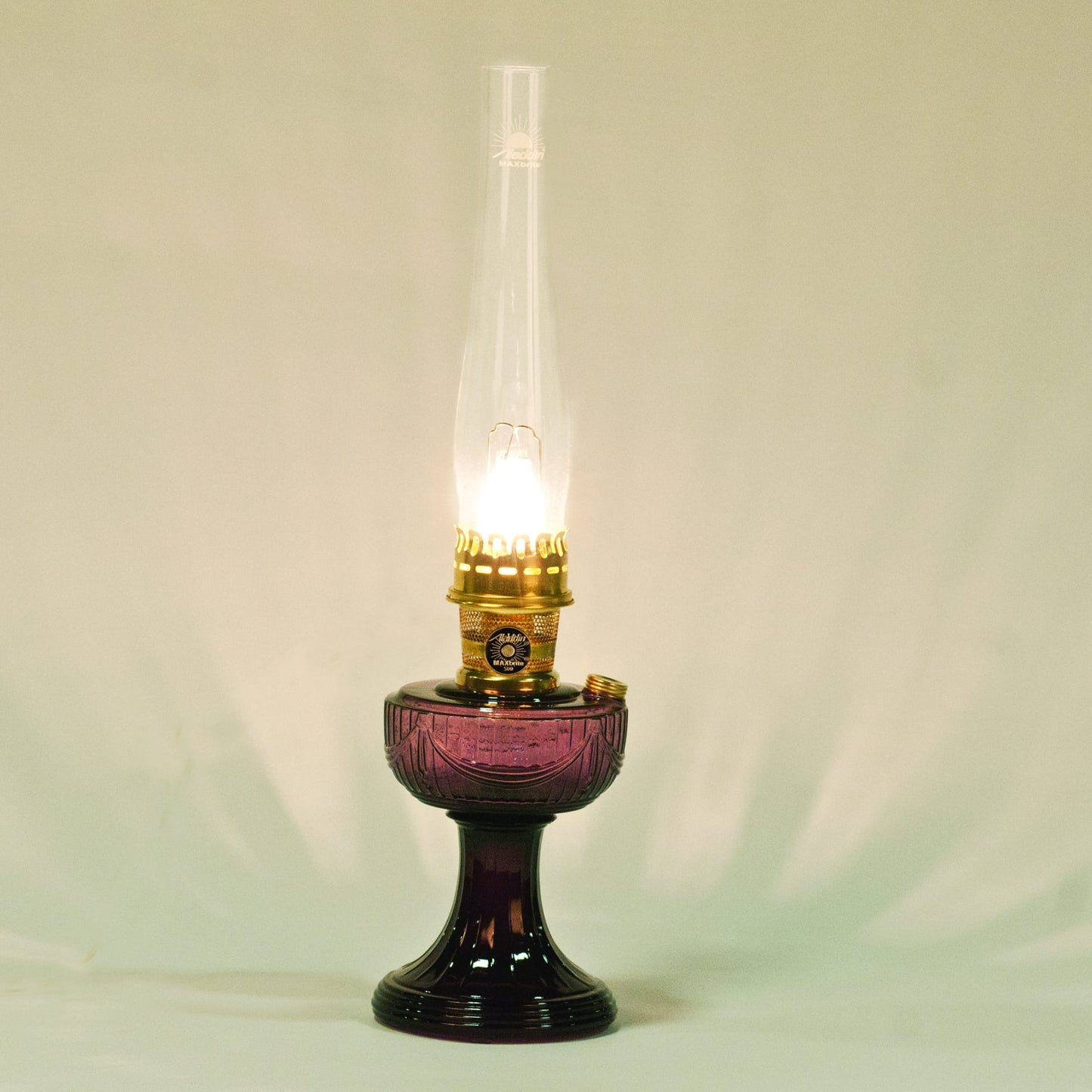 Handcrafted purple Lincoln Drape glass oil lamp with clear tall chimney and brass burner illuminated, ideal for Farm, Garden & Tool, Lamps & Lighting, Oil Lamps, Table Lamps, Best Sellers, Homesteading, and Promo Eligible collections.