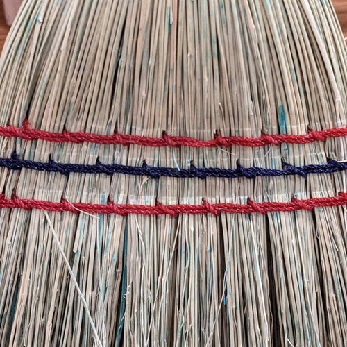 Close-up of hand-stitched natural corn straw bristles bound with red and blue threads on a handcrafted Amish-made child’s broom, featured in Home & Decor and Children's Toys collections.