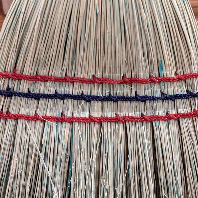 Close-up of hand-stitched natural corn straw bristles bound with red and blue threads on a handcrafted Amish-made child’s broom, featured in Home & Decor and Children's Toys collections.