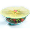 Yellow silicone reusable bowl cover shaped like a lily pad sealing a glass bowl filled with fresh lettuce and cherry tomatoes, featured in Kitchen & Food and Storage and Serving collections.
