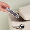 Hand holding a clear plastic magnet housing designed to prevent mineral stains, being placed inside a beige toilet tank, featured in Home & Decor and Household Cleaning collections.