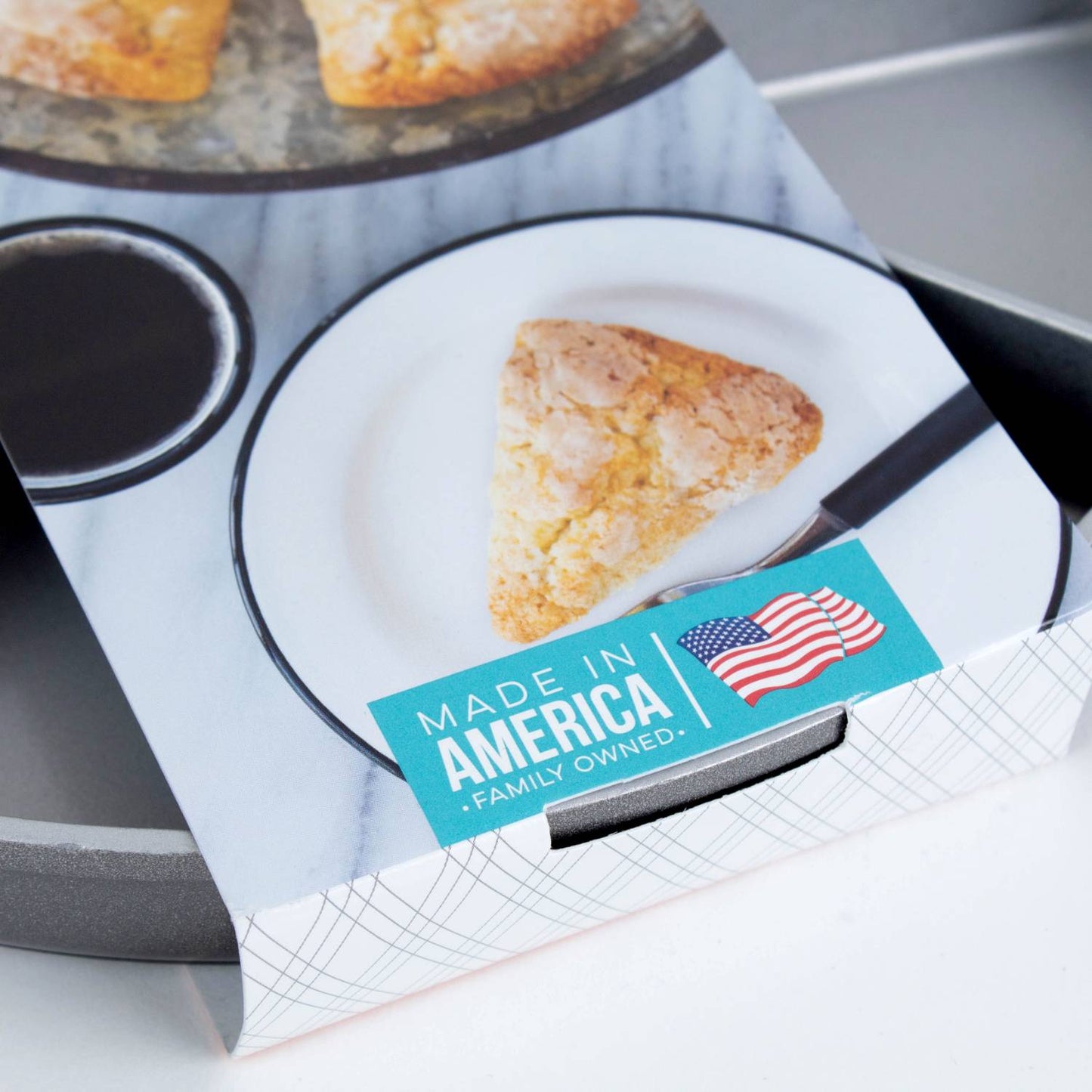 Single golden-baked scone wedge on white plate with black rim beside a cast aluminum pan, highlighting handcrafted American-made cookware in Kitchen & Food, Farm, Garden & Tool collections.