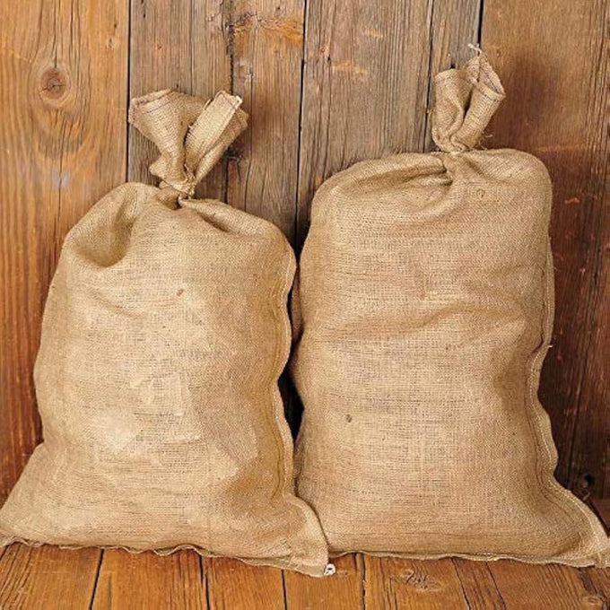 Two handcrafted burlap bags made from natural fibers, tied at the top, resting against a rustic wooden backdrop, featured in Farm, Garden & Tool and Garden Accessories collections.