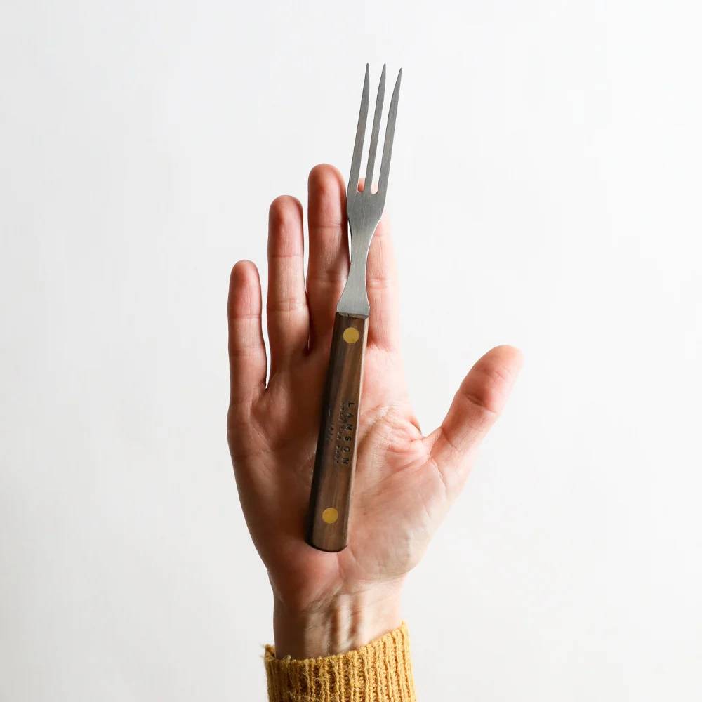 Handheld old-fashioned kitchen fork with three stainless steel tines and a brass-riveted dark brown hardwood handle, handcrafted in USA, ideal for cooking and grilling tasks.