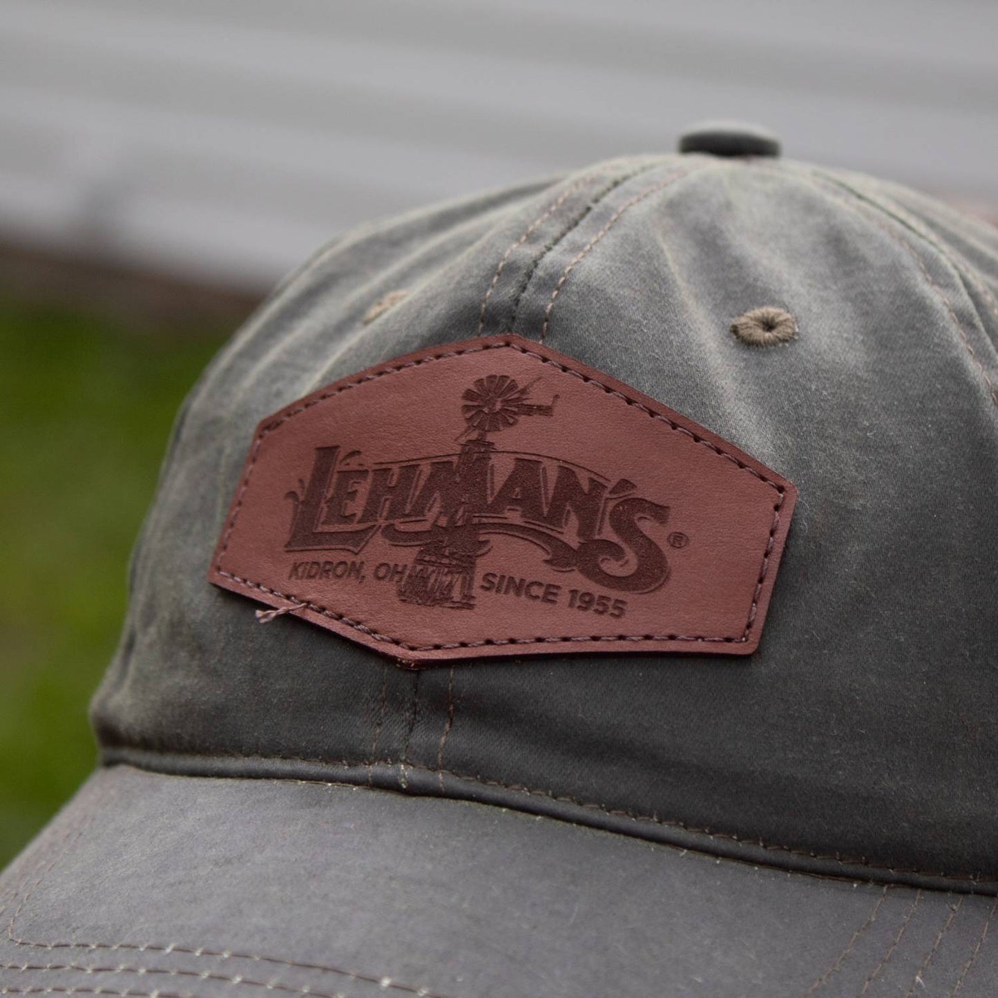 Close-up of an adjustable washed cotton hat with a weathered retro look, featuring a handcrafted light brown leather patch embossed with a windmill design, perfect for Health & Wellness, Clothing and Accessories, Best Sellers, and Promo Eligible collections.