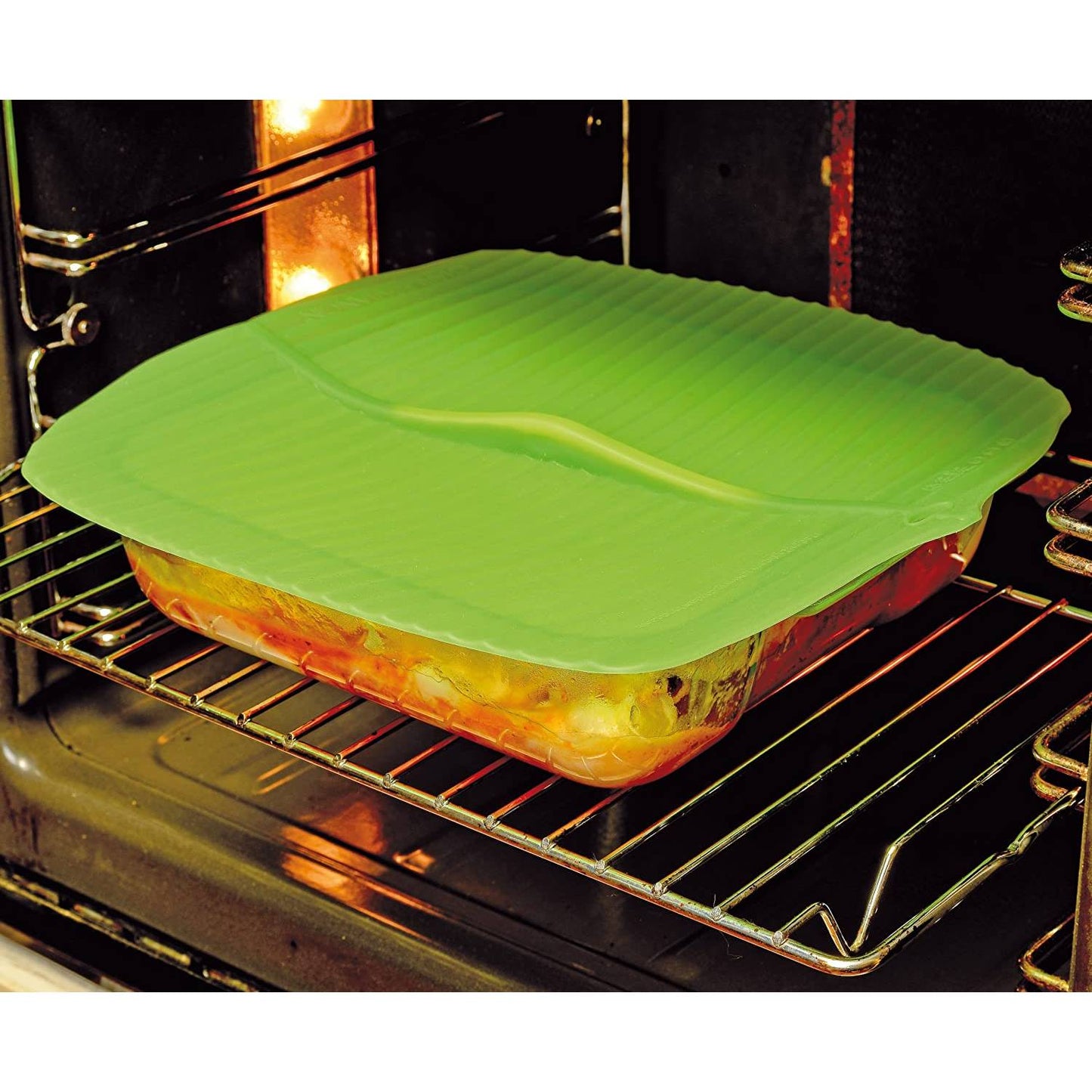 Translucent green reusable silicone bowl cover with banana leaf design sealing a glass baking dish inside an oven, made from food-grade material for Kitchen & Food, Kitchen Gadgets, and Storage and Serving collections.