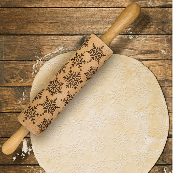 Beechwood rolling pin with embossed snowflake pattern, gently pressing detailed designs into cookie dough, perfect for Kitchen & Food, Cookware, and Baking Supplies collections.