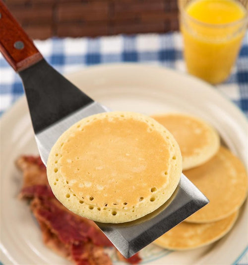 Heavy-duty stainless steel spatula with hardwood handle and brass rivets, shown lifting a pancake; ideal for Kitchen & Food, Storage and Serving, Best Sellers, and Promo Eligible collections.