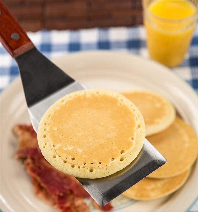 Heavy-duty stainless steel spatula with hardwood handle and brass rivets, shown lifting a pancake; ideal for Kitchen & Food, Storage and Serving, Best Sellers, and Promo Eligible collections.