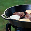 Close-up of a large cast iron skillet cooking four cheeseburgers outdoors on a portable stove, showcasing durable cookware from Kitchen & Food and Cookware collections, USA made.