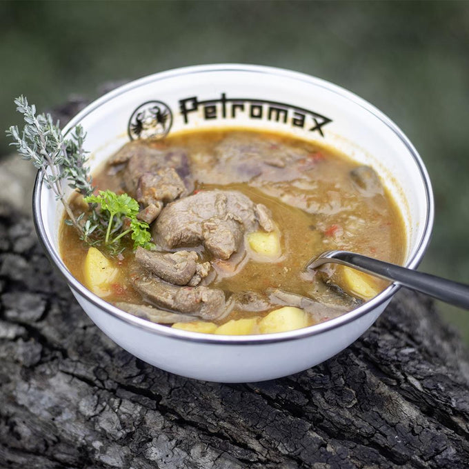 White enamel bowl with Petromax logo filled with hearty stew of meat and potatoes, garnished with fresh herbs, ideal for Camping, Kitchen & Food, Farm, Garden & Tool, and Dinnerware collections