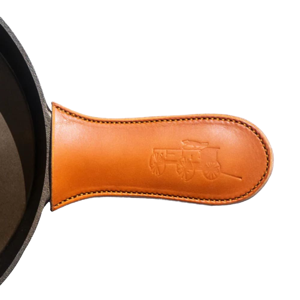 Handcrafted American vegetable-tanned leather handle cover with embossed wagon design, protecting hands from heat on cast iron skillets, ideal for Kitchen & Food and USA Made collections.