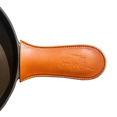 Handcrafted American vegetable-tanned leather handle cover with embossed wagon design, protecting hands from heat on cast iron skillets, ideal for Kitchen & Food and USA Made collections.