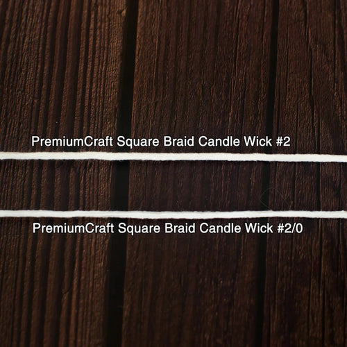 Close-up of two white square braided candle wicks laid horizontally on a dark wooden surface, suitable for use in candle making and included in lamps and lighting collections.