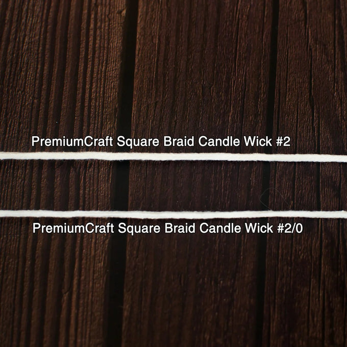 Close-up of two white square braided candle wicks laid horizontally on a dark wooden surface, suitable for use in candle making and included in lamps and lighting collections.
