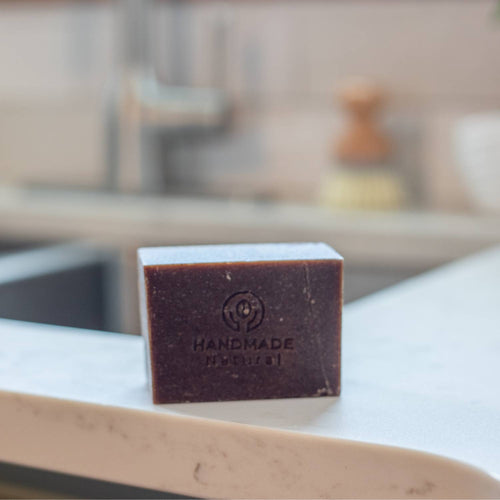 Handcrafted natural dish bar soap with embossed logo, displayed on a kitchen countertop, highlighting chemical-free cleaning in Home & Decor and Household Cleaning collections.