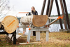 Portable chain sawmill with sturdy metal frame and orange accents, supporting large logs outdoors near a lake, featured in Farm, Garden & Tool, Wood Cutting and Hauling, and Best Sellers collections.