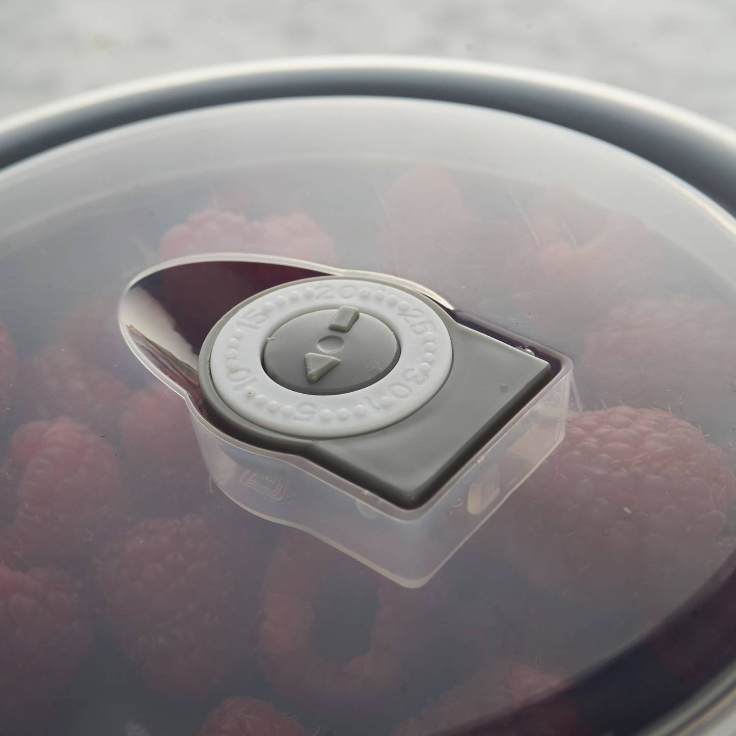 Close-up of a translucent airtight lid with vent dial on a cream-colored all-purpose bowl containing fresh raspberries, ideal for Kitchen & Food, Cookware, Baking Supplies, Storage and Serving, Best Sellers, and Promo Eligible collections.