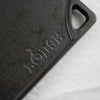 Close-up of a durable black cast iron griddle corner with a built-in handle and embossed brand name, part of USA made cookware for kitchen and food collections.