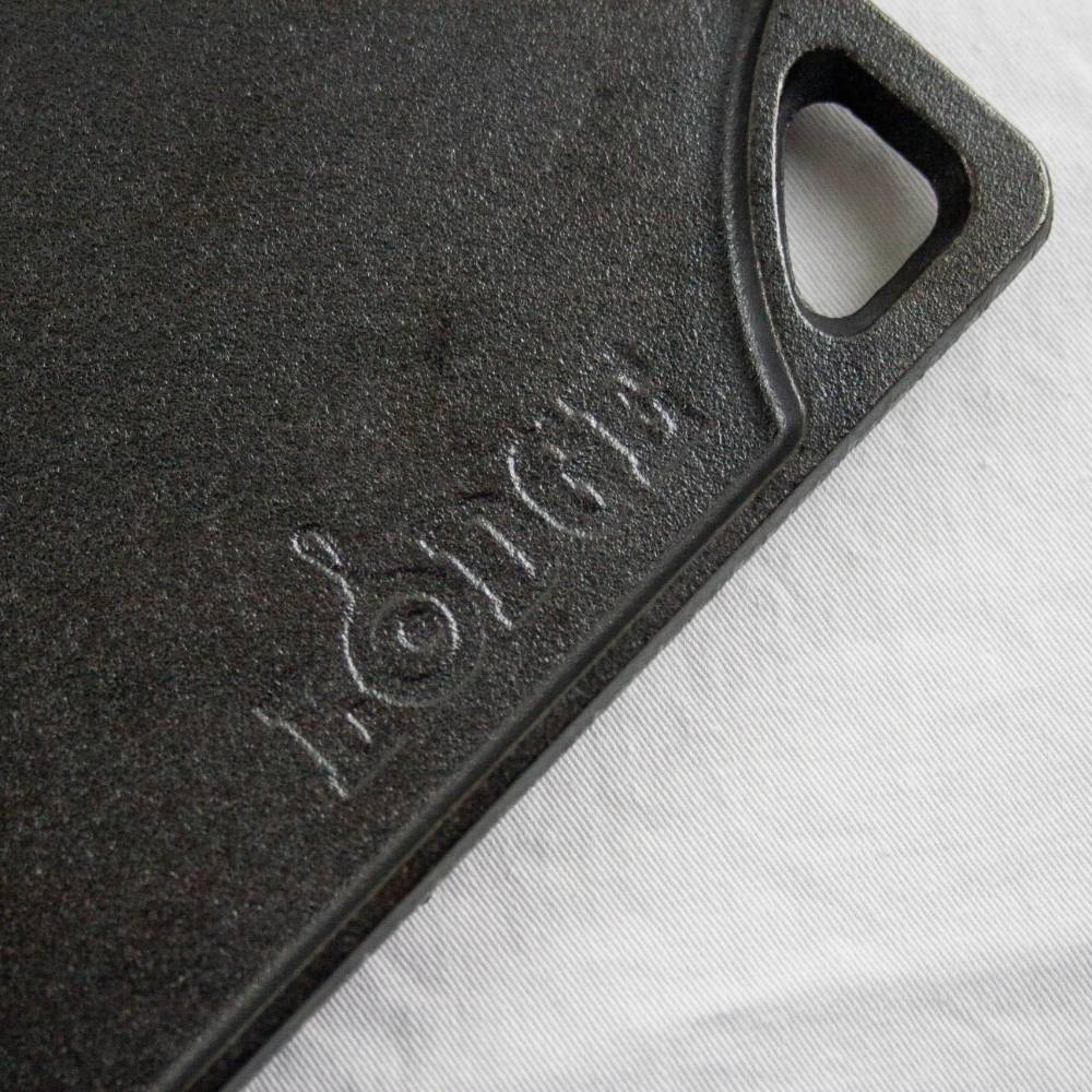 Close-up of a durable black cast iron griddle corner with a built-in handle and embossed brand name, part of USA made cookware for kitchen and food collections.