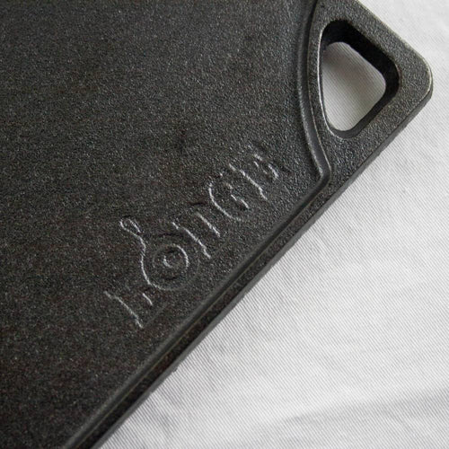 Close-up of a durable black cast iron griddle corner with a built-in handle and embossed brand name, part of USA made cookware for kitchen and food collections.