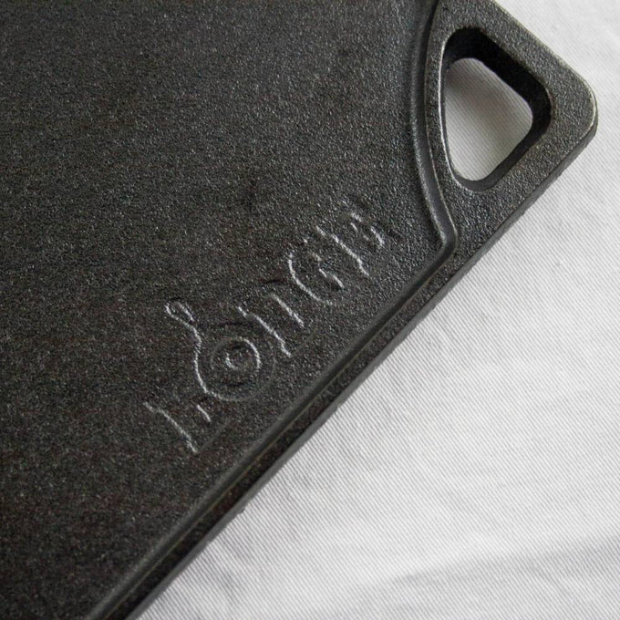 Close-up of a durable black cast iron griddle corner with a built-in handle and embossed brand name, part of USA made cookware for kitchen and food collections.