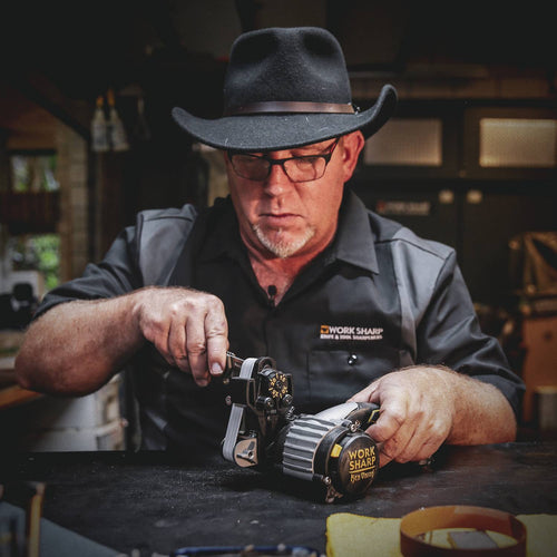 Man wearing black hat and glasses using a Work Sharp Knife and Tool Sharpener with adjustable dials and abrasive belts, featured in Kitchen & Food, Food Prep, and Best Sellers collections.