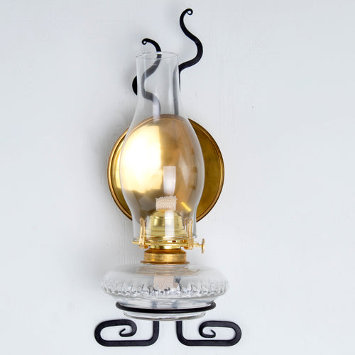 Wall-mounted oil lamp with clear glass chimney, solid brass reflector, and decorative black metal bracket, highlighting handcrafted USA made quality in Lamps & Lighting and Oil Lamps collections.