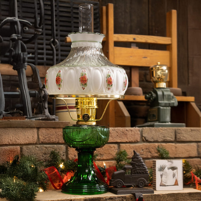 Handcrafted oil lamp with a rich emerald green glass base and ornate white glass font decorated with floral accents, featuring brass trim, ideal for Lamps & Lighting and Table Lamps collections.