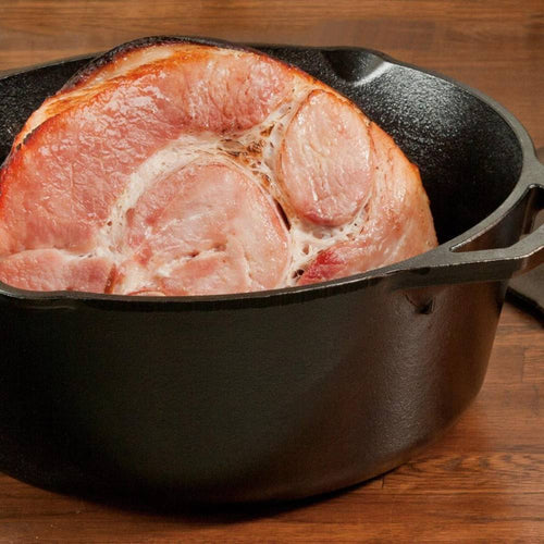 Handcrafted Lodge cast iron Dutch oven made in USA featuring durable construction and heat retention, shown with a large cooked ham inside, ideal for Kitchen & Food, Cookware, Cast Iron, USA Made, Best Sellers, Promo Eligible collections.
