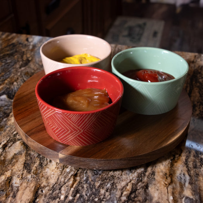 Round wooden turntable with three ceramic condiment bowls in red, beige, and green holding ketchup, mustard, and barbecue sauce, designed for easy serving in Kitchen & Food collections.