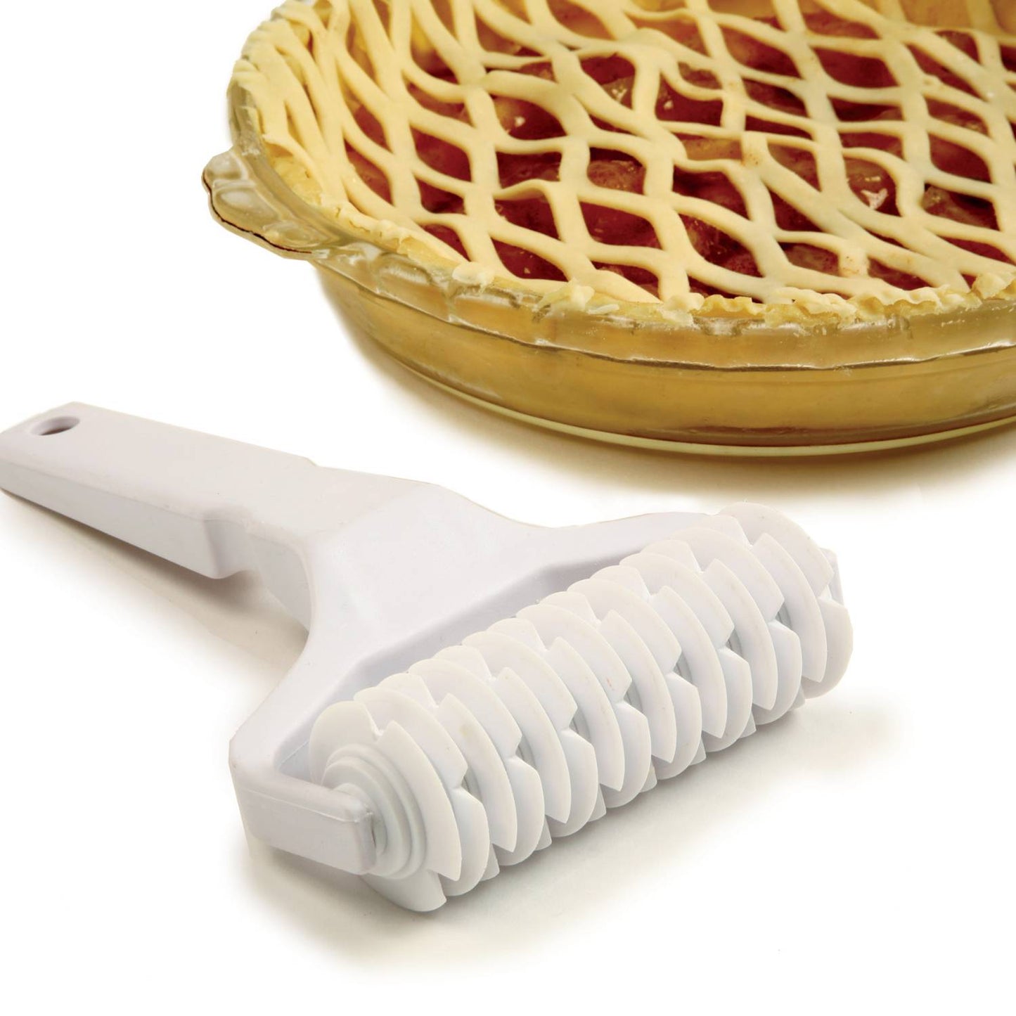 White heavy-duty plastic lattice cutter with multiple evenly spaced blades, resting beside a glass pie dish filled with cherry pie and topped with a perfectly woven lattice crust, suitable for Kitchen & Food, Baking Supplies, and Cookware collections.
