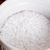 Close-up of white potassium hydroxide flakes in a white container, used in liquid soapmaking, featured in Health & Wellness, Soapmaking Supplies, and USA Made collections.