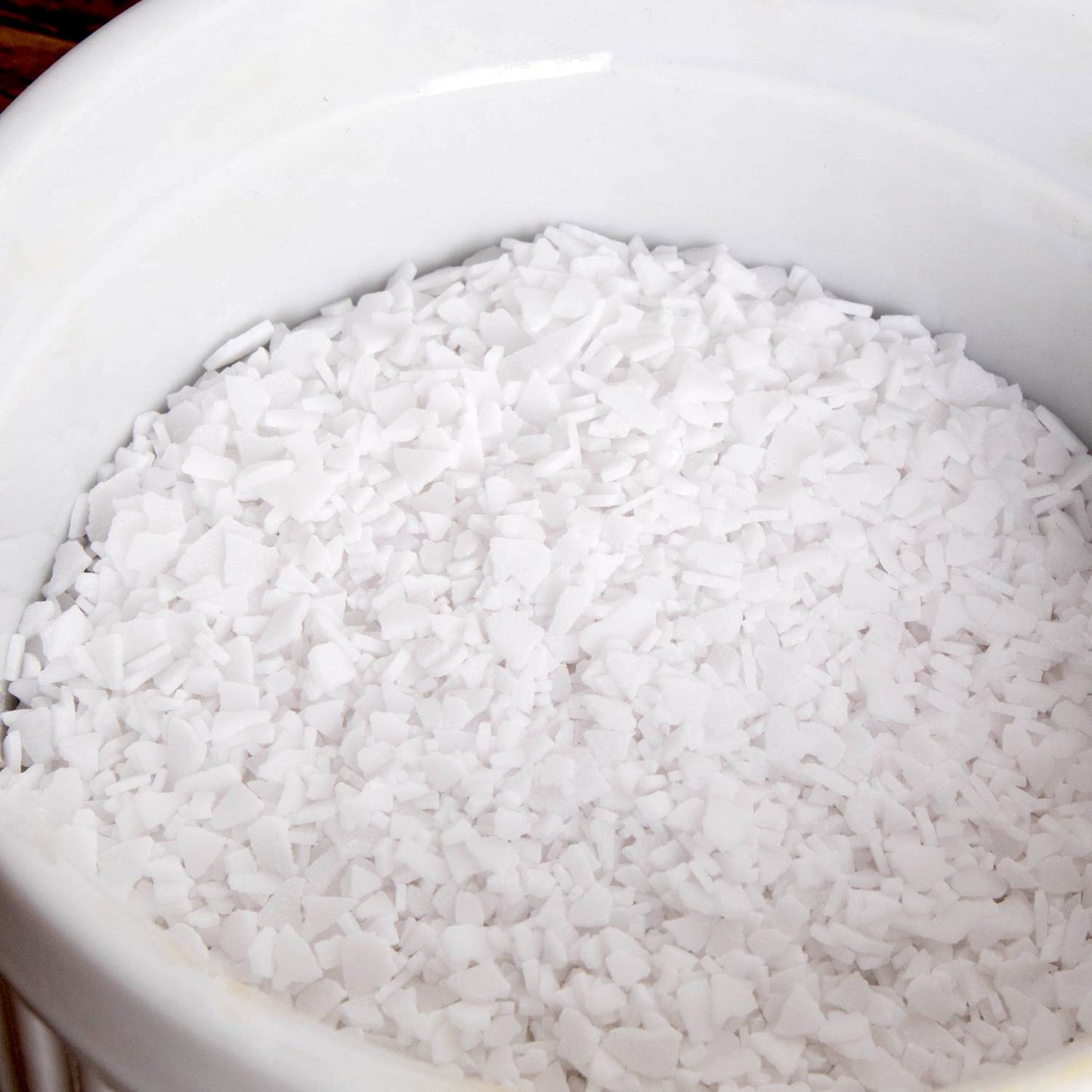 Close-up of white potassium hydroxide flakes in a white container, used in liquid soapmaking, featured in Health & Wellness, Soapmaking Supplies, and USA Made collections.
