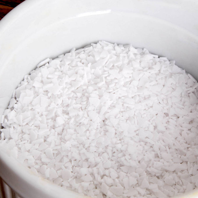 Close-up of white potassium hydroxide flakes in a white container, used in liquid soapmaking, featured in Health & Wellness, Soapmaking Supplies, and USA Made collections.