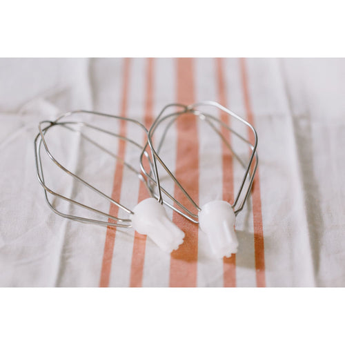 Two handcrafted batter whisk attachments with polished metal wires and white plastic connectors, resting on a striped kitchen towel, ideal for Kitchen & Food and Baking Supplies collections.