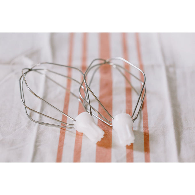 Two handcrafted batter whisk attachments with polished metal wires and white plastic connectors, resting on a striped kitchen towel, ideal for Kitchen & Food and Baking Supplies collections.