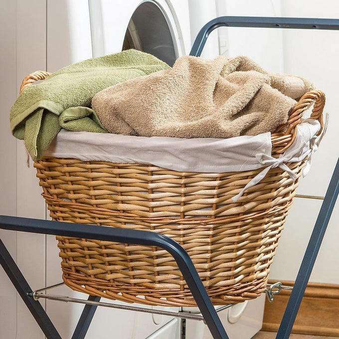 Handwoven split willow laundry basket with cloth lining and rope handles holding towels, ideal for small loads and delicates in laundry supplies and home decor collections.