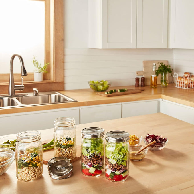Two wide mouth glass jars with stainless steel lids filled with fresh chopped vegetables and two empty matching jars on a wooden kitchen counter, part of Kitchen & Food, Storage and Serving, Best Sellers, and Promo Eligible collections.