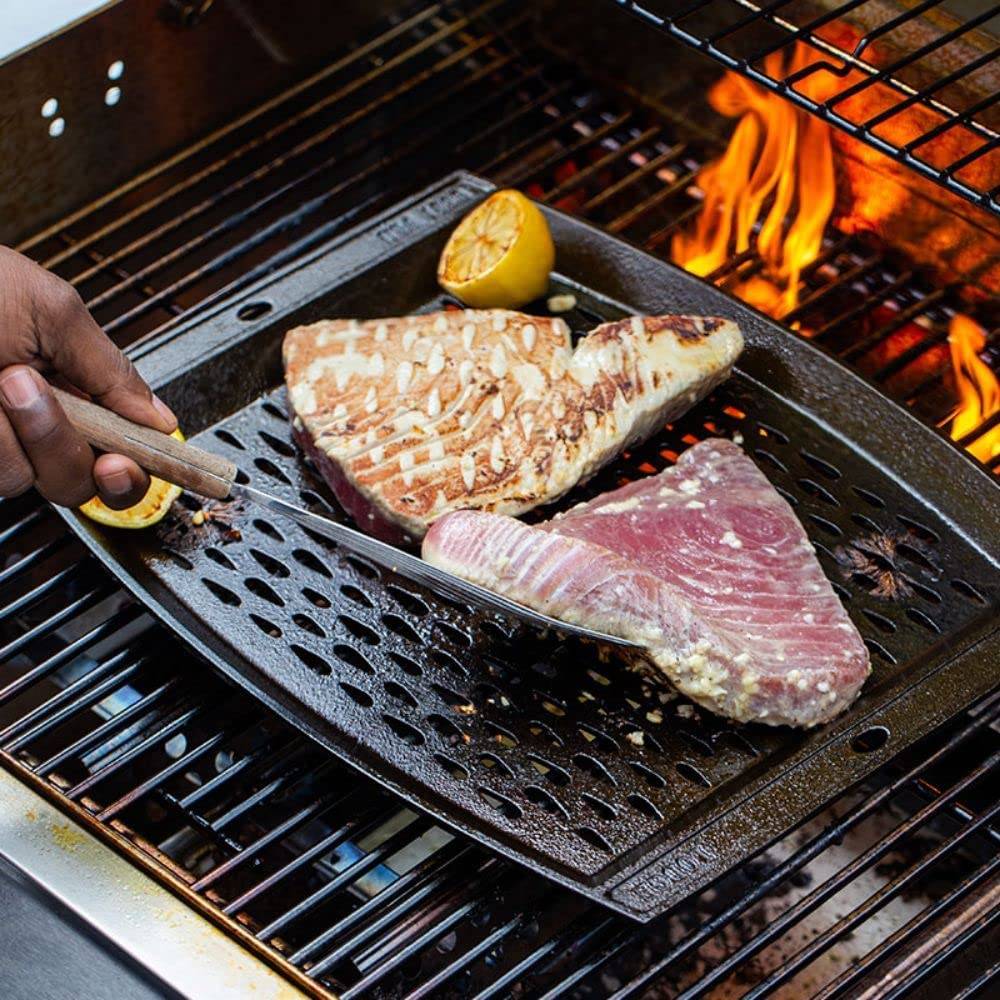 Handcrafted cast iron grill topper pan with perforated surface for enhanced smoky flavor, shown grilling tuna steaks and lemon halves, ideal for Kitchen & Food and Cast Iron collections.