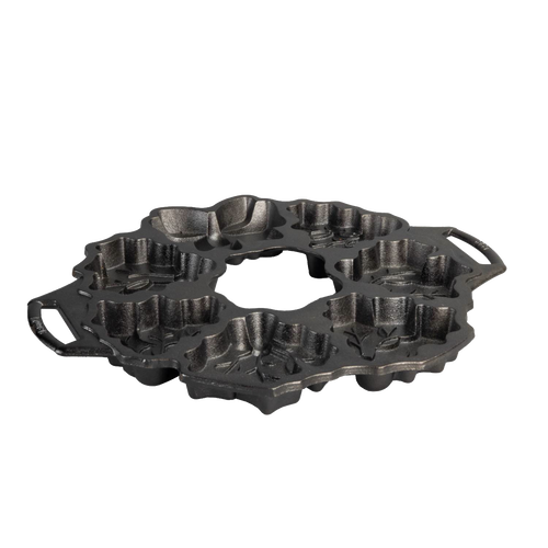 Seasoned cast iron cakelet pan shaped with festive holiday wreath motifs including holly and berries, featuring dual handles for easy handling, ideal for Kitchen & Food and Cast Iron collections.
