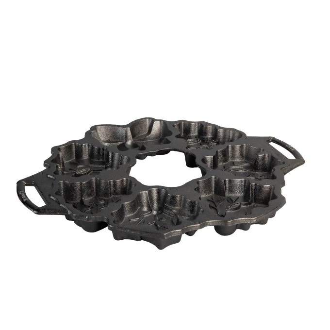 Seasoned cast iron cakelet pan shaped with festive holiday wreath motifs including holly and berries, featuring dual handles for easy handling, ideal for Kitchen & Food and Cast Iron collections.