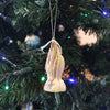 Handcrafted olive wood ornament featuring detailed praying hands hanging on a Christmas tree with colorful holiday lights, ideal for Home & Decor and Holiday Decor collections.