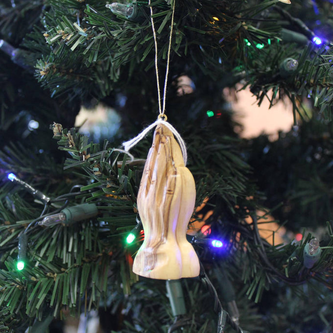 Handcrafted olive wood ornament featuring detailed praying hands hanging on a Christmas tree with colorful holiday lights, ideal for Home & Decor and Holiday Decor collections.
