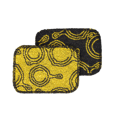 Two non-abrasive scrub cloths with skillet patterns in yellow and black, designed for gentle cookware cleaning, made in USA, featured in Kitchen & Food and Cast Iron collections.