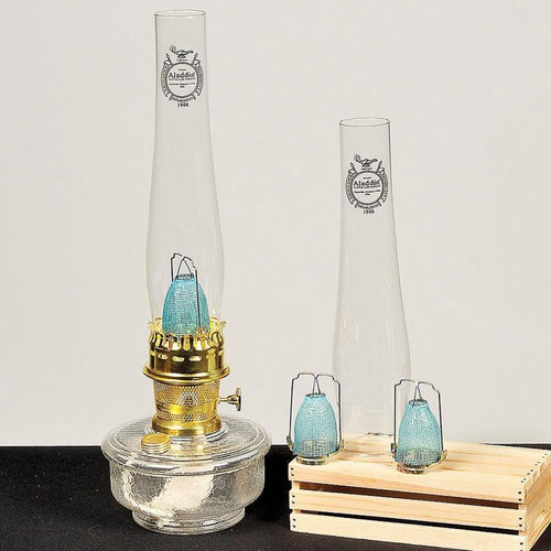 Glass oil lamp with dimpled fuel bowl, brass burner with brass filler cap, and protective blue mantle, suitable for farm, garden, and homesteading lighting needs.