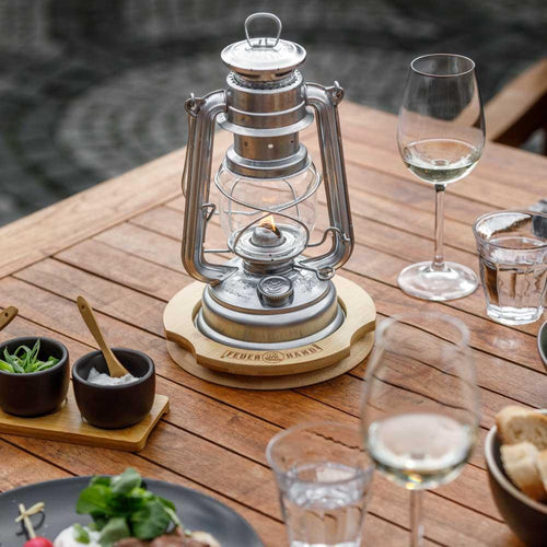 Unique handcrafted bamboo coaster with engraved logo, designed to protect surfaces from oil while using vintage-style lanterns, ideal for camping and outdoor lighting setups.